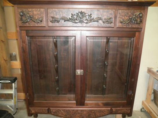 Wooden display cabinet with glass doors and intricate carvings.