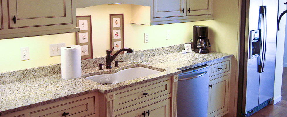Elegant kitchen sink area with granite countertop and cream cabinetry.